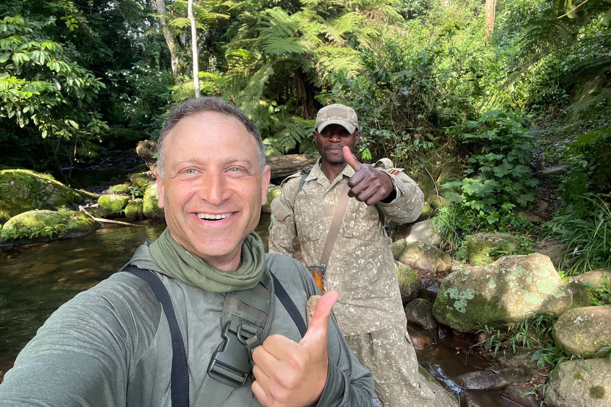 Jonathan Silverman and a Volcanoes Safaris guide giving a thumbs-up before starting their gorilla trekking adventure at Bwindi Lodge, Uganda.