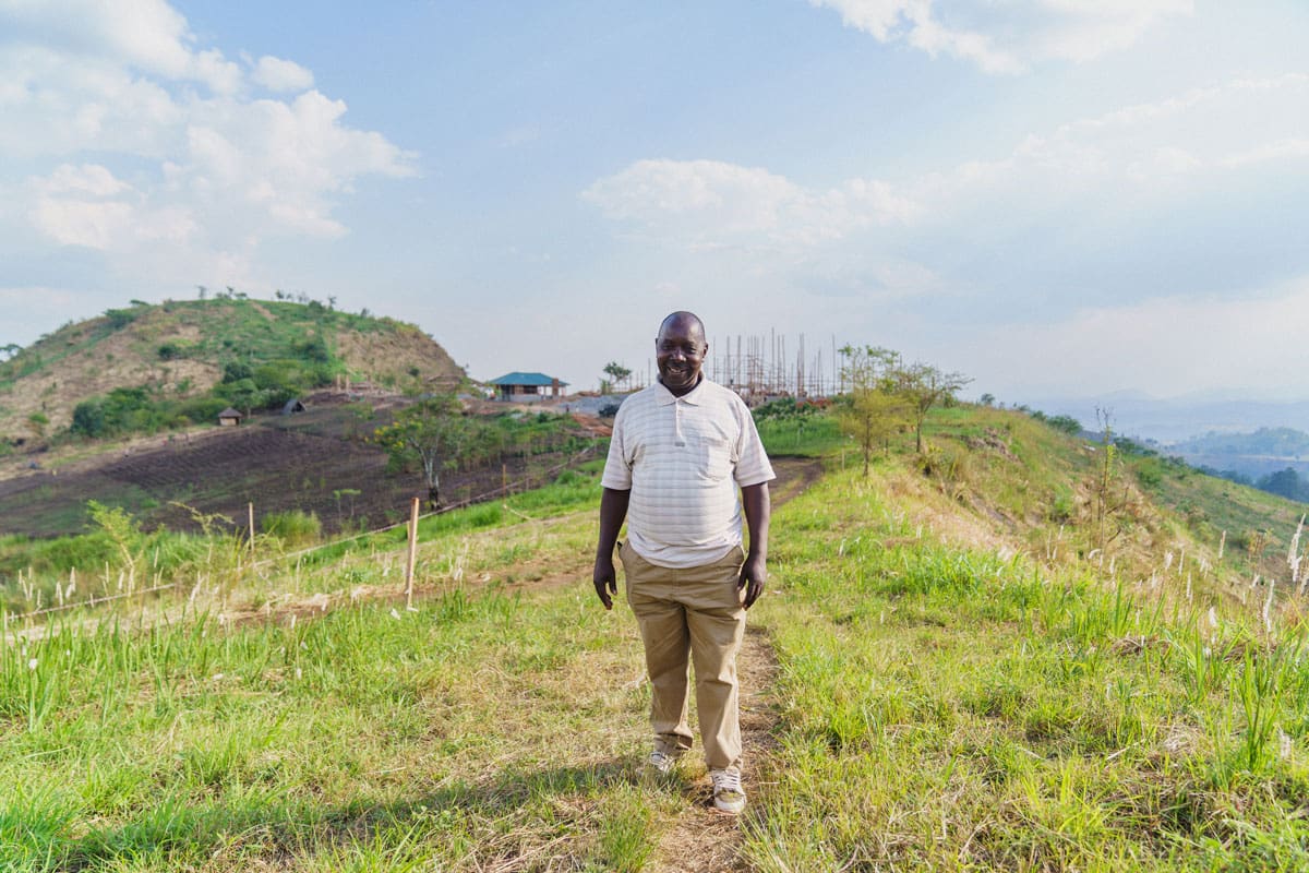 Cyprien Serugero, the construction manager for Volcanoes Safaris, stands proudly on the path leading to the Kibale Lodge development site, with the beautiful landscape of Uganda stretching out behind him.