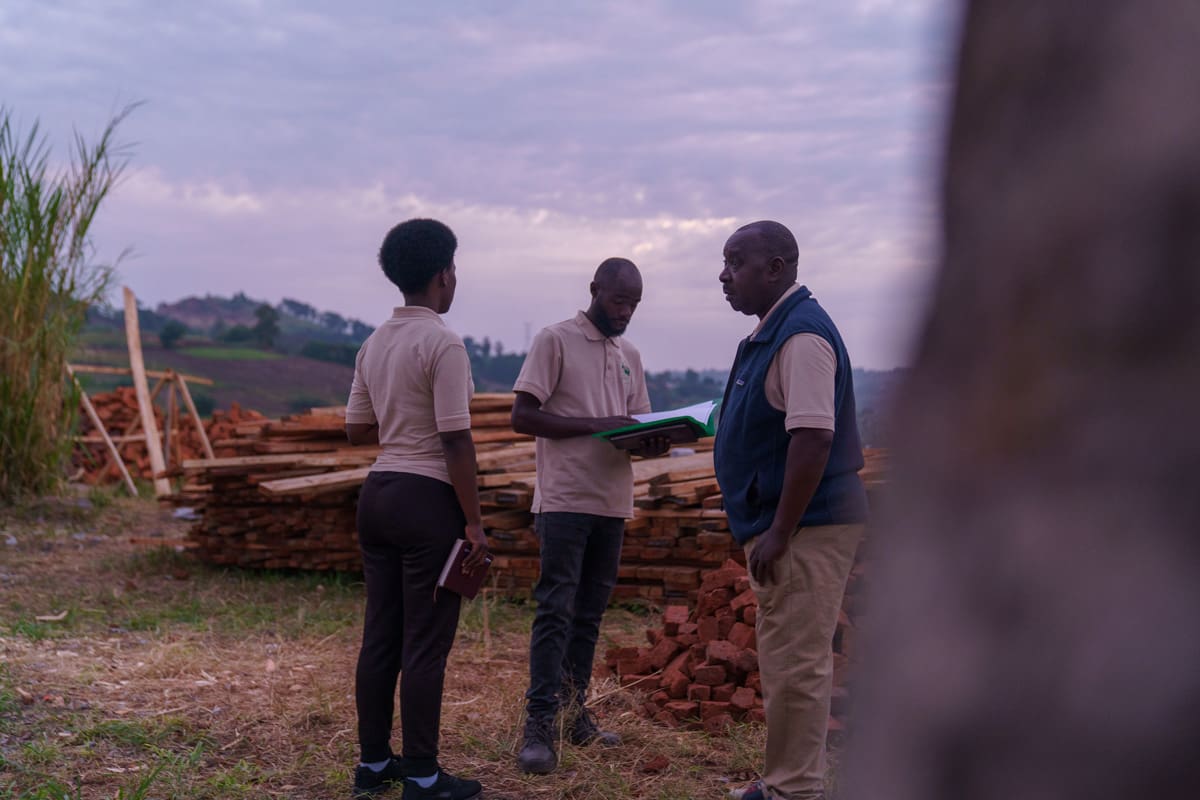 Celine, the botanist for Volcanoes Safaris, and Cyprien Serugero, the construction manager, engaged in a focused discussion on site, surrounded by the materials that will contribute to the sustainable development of Kibale Lodge.