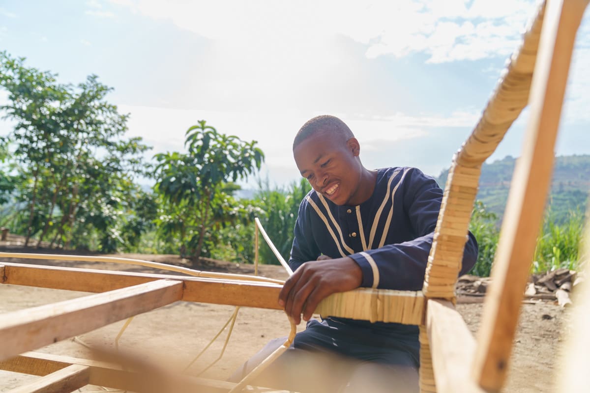 A skilled member of the Volcanoes Safaris construction team focuses intently on handcrafting furniture, adding a personal touch to the sustainable development of the Kibale Lodge in Uganda.